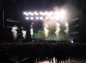 Smoke jets and stage lights over a concert crowd