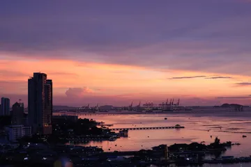 A harbour city at dusk, cranes and piers under a pink sky