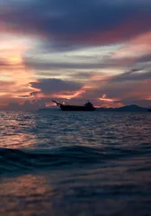 A ship silhouetted on the sea under a pink and purple sunset